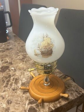 Vintage nautical table lamp with a ship's wheel base and sailing ship shade